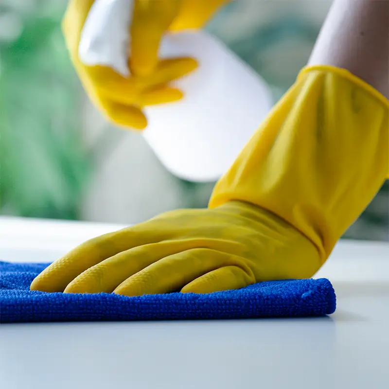 Yellow gloves cleaning a surface